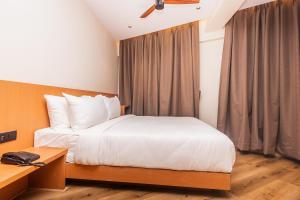 a bedroom with a white bed and a desk and a window at RaRa Residence in Mumbai