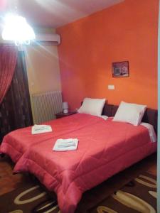 a bedroom with a red bed with towels on it at Hotel Aoos in Konitsa