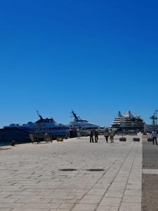 a group of people walking on a pier with ships at Suite Crystal Home with Jacuzzi in Trapani