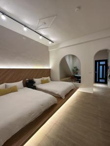 two beds in a large room with white walls at Tainan Little Day in Tainan