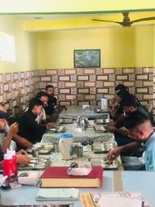 a group of men sitting at a table eating food at Hotel Him darshan in Madheso