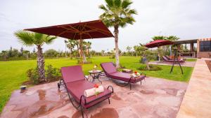 two chairs and an umbrella on a patio at Igrane House - Resort & Spa in Aït Faska