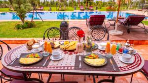 a table with plates of food on it next to a pool at Igrane House - Resort & Spa in Aït Faska
