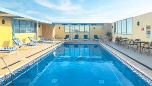 a swimming pool with chairs and tables in a building at Plazza In Hotel in Doha