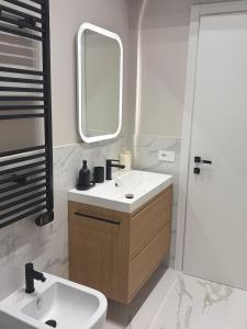 a white bathroom with a sink and a mirror at Aura Suite in Parma