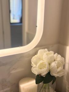 a vase with white flowers in front of a mirror at Aura Suite in Parma