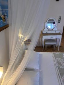 a bedroom with a bed with white curtains and a mirror at Isidora Hotel in Agia Marina Aegina