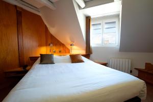 a large white bed in a room with a window at Hotel Restaurant Père Benoît in Entzheim