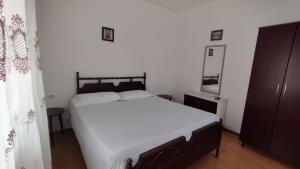 a bedroom with a large white bed and a mirror at Lili's House in Delvinë
