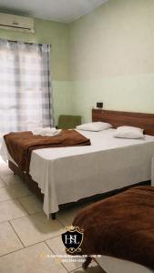 a bedroom with two beds and a window at Hotel São Luiz Iraí in Iraí