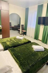 a hotel room with two beds with green blankets at Готель «ТАВЕРНА» in Ovruch