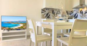 a white dining room with a white table and a tv at Dimora Mary - Vicino al mare in La Maddalena