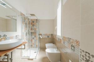 a bathroom with a sink and a toilet and a mirror at Ponente & Maestro Rooms in Favignana