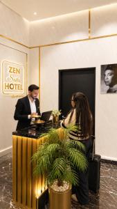a man and a woman standing at a desk in a lobby at ZEN Suites Hotel Massira in Casablanca