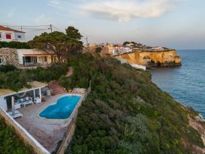 a swimming pool on a hill next to the ocean at Refugio in Carvoeiro