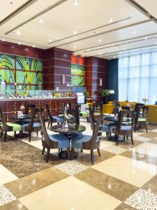 a restaurant with tables and chairs and a bar at Plazza In Hotel in Doha