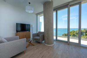 a living room with a couch and a tv and large windows at Green Cape Botanico in Batumi