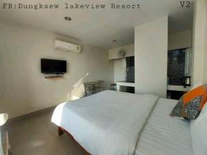 a bedroom with a large white bed and a tv at Dungkaew lakeview resort in Amphoe Ban Dung