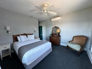 ein Schlafzimmer mit einem Bett und einem Stuhl und einem Deckenventilator in der Unterkunft National Hotel in New Shoreham