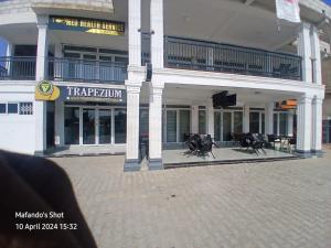 a large building with tables and chairs in front of it at Trapezium Lodge in Amasaman