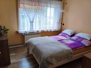 a bedroom with a large bed with purple sheets and a window at Apartament Przy Puszczy Białowieskiej in Hajnówka