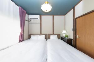 two beds in a room with two windows at Nagoya JADE GRACE in Nagoya