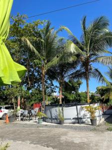 a patio with palm trees and chairs and a fence at Hibiscus holiday in Capesterre-Belle-Eau