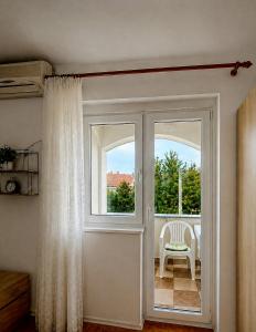 a white door with a window and a chair at Apartmani Kasteljan 4, Stara Novalja in Stara Novalja