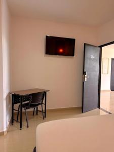 a room with a table and a television on the wall at Hotel Confort Ariari in Granada