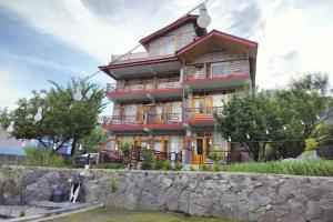 a large building with a stone wall in front of it at Mountainshack Riverside Stay & Cafe in Kulu