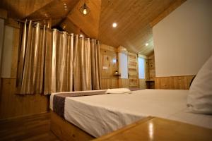a bedroom with a large bed in a wooden room at Mountainshack Riverside Stay & Cafe in Kulu
