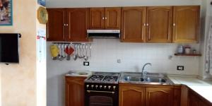 a kitchen with wooden cabinets and a stove and a sink at Casa vacanze Malinini in Savogna
