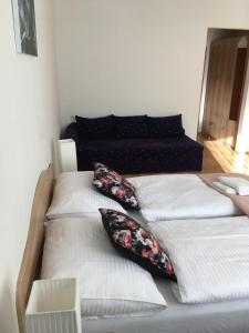 two beds with pillows in a room with a couch at Penzión Kýčera in Oščadnica