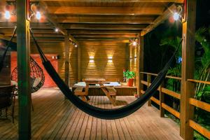 a hammock on the deck of a wooden house at Pousada Gauleses - Refugio de Charme na Praia do Rosa by La Vem Férias in Praia do Rosa