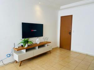 a living room with a flat screen tv on a white wall at PRAIA DO MORRO NA QUADRA DO MAR com 2 Quartos sendo 1 Suíte mais Kit Praia e ao lado PRAIA CENTER in Guarapari