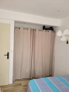 a bedroom with white curtains and a ceiling fan at Hibiscus holiday in Capesterre-Belle-Eau