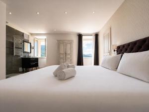 a large white bed with two stuffed animals on it at Hôtel Villa Les Orangers in Olmeto
