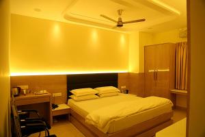 a bedroom with a bed and a desk with a ceiling at Elite Residency Bhadrachalam in Bhadrāchalam