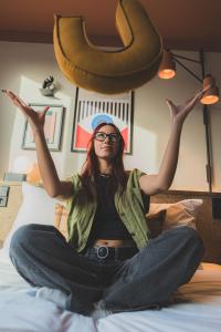 a woman sitting on a bed with her arms in the air at The Usual Brussels in Brussels
