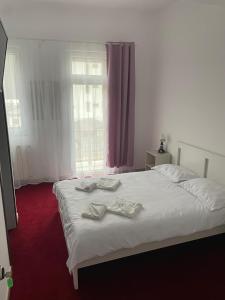 a bedroom with a white bed with two towels on it at Hotel Eurosan in Slănic-Moldova