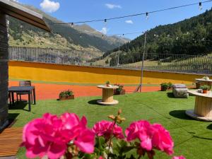 a patio with tables and pink flowers on a roof at Wuau! Hotel Galanthus & Spa in Soldeu +114 photos