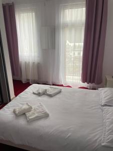 a bed with two towels on it with a window at Hotel Eurosan in Slănic-Moldova +2 photos