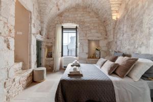 a bedroom with a large bed and a stone wall at Ostuni Luxury Stay - 2 Jacuzzi in Ostuni