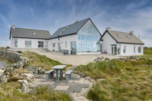 a house with a bench in front of it at Doleen Quay House in Ballyconneely