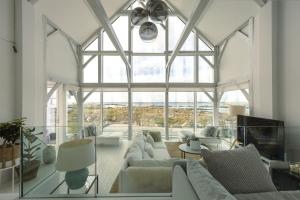a living room with white furniture and a large window at Doleen Quay House in Ballyconneely