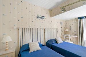 a bedroom with two beds and a wall covered in wallpaper at Chambres Escale Pontilabienne in Pont-lʼAbbé-dʼArnoult