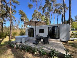 an rv with a table and an umbrella at Ferienhäuser Insel Usedom - Luxuswohnwagen Doppeltür mit Whirlpool in Lütow