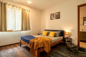 a bedroom with a bed with yellow pillows and a window at LiveAway Bengaluru, HSR by PACK in Bangalore