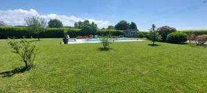 a green yard with a swimming pool in the background at Le Clos des 4 Saisons in La Rochepot