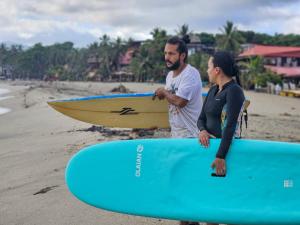 a man and a woman standing on the beach with a surfboard at Natyva House in Guachaca +46 photos